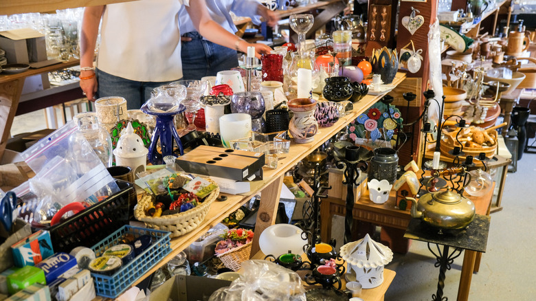 People browsing a thrift store filled with ceramics, glasswares, and trinkets