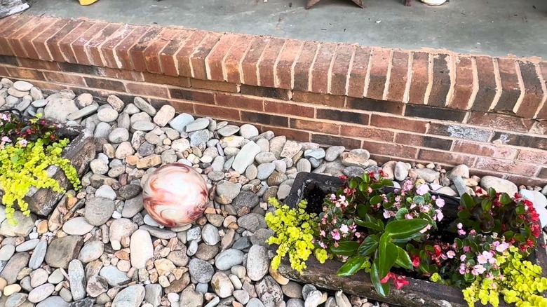 A red bowling bawl on garden stones between two planters