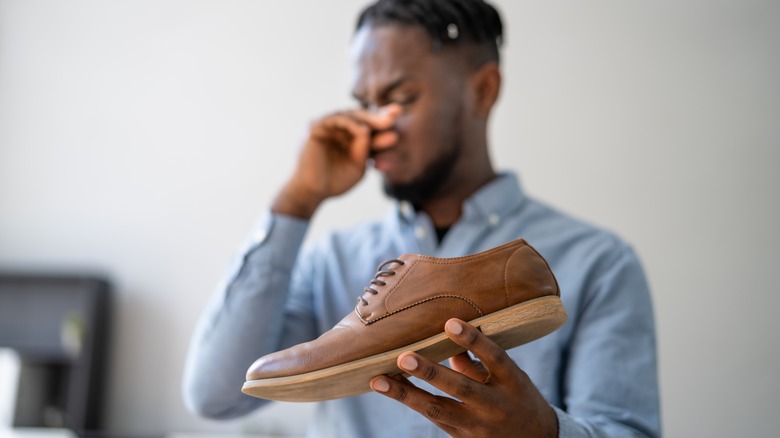 man holding smelly shoes