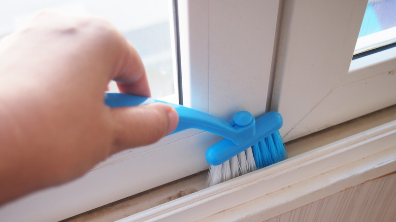 person cleaning window tracks