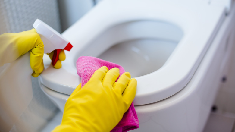 gloved hands cleaning toilet