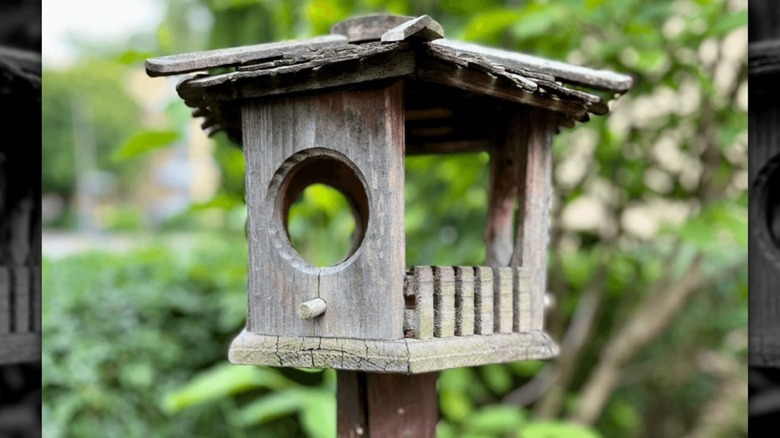 A rustic wooden birdhouse on a DIY wood fence post base