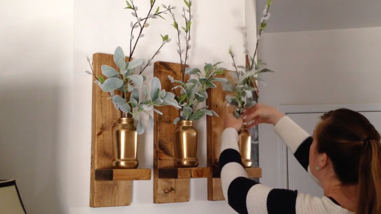 DIY wall shelves holding gold decorations made from scrap fence wood