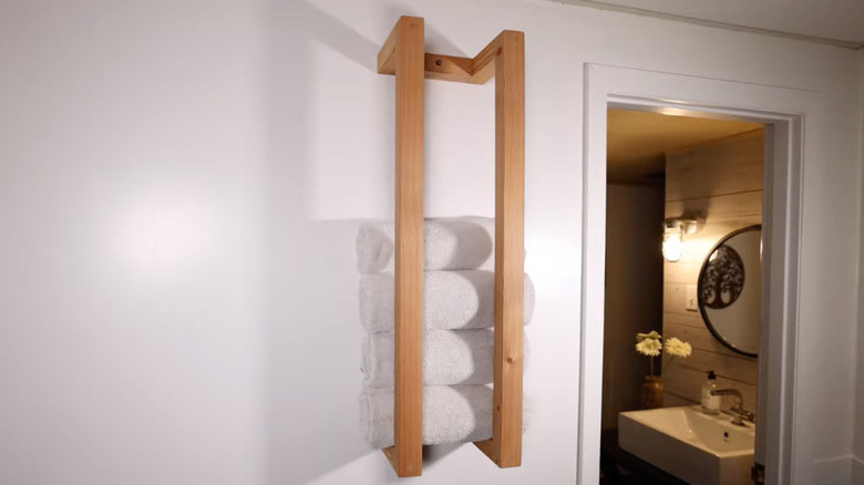 A wall-mounted towel rack holding white towels.