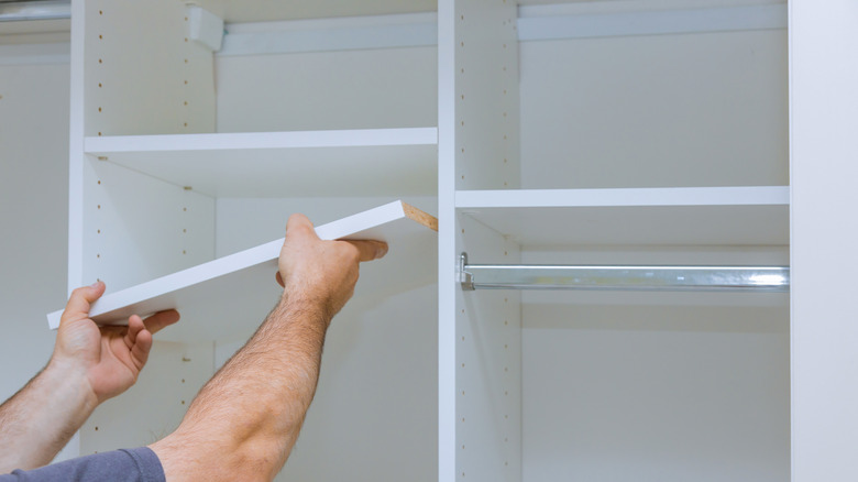 Person putting shelf in closet