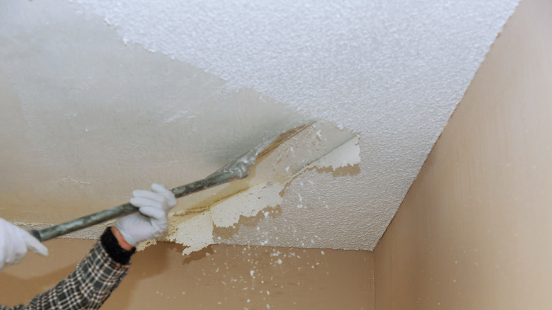 person removing popcorn ceiling