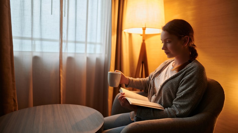 woman reading book with lamp