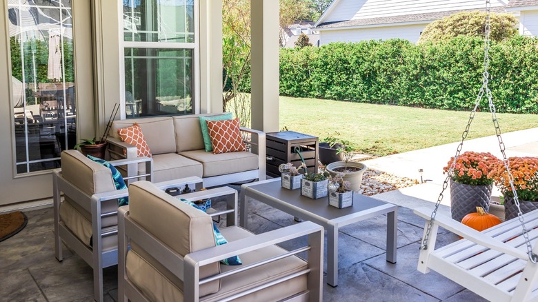 Small patio with fan, couch, swing, table, and plant pots