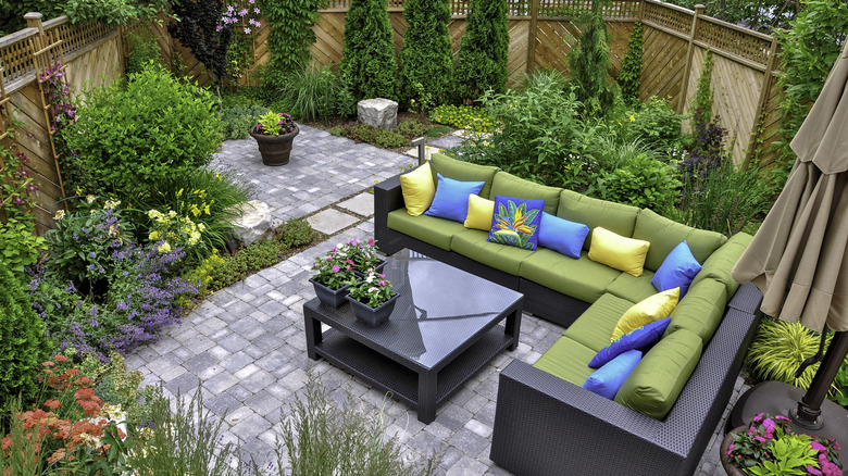 Couch, colorful cushions, and flowers in backyard space