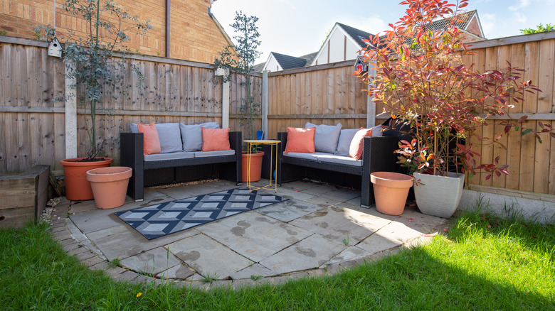 Concrete patio with couch, table, and plant pots