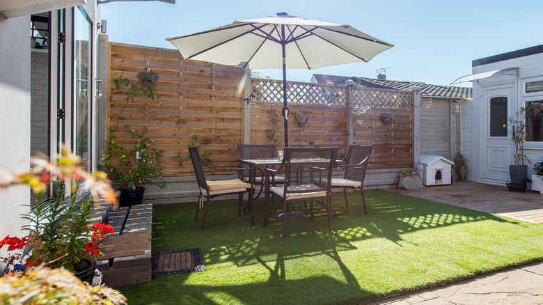 Umbrella shading chair and table on faux grass