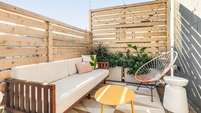 Sofa, table, and chair on patio surrounded by fence and walls