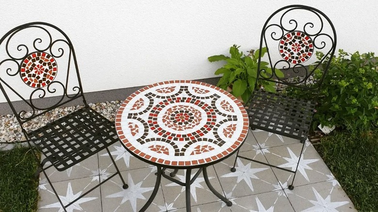 Patterned tiles and mosaic table and chair on small patio