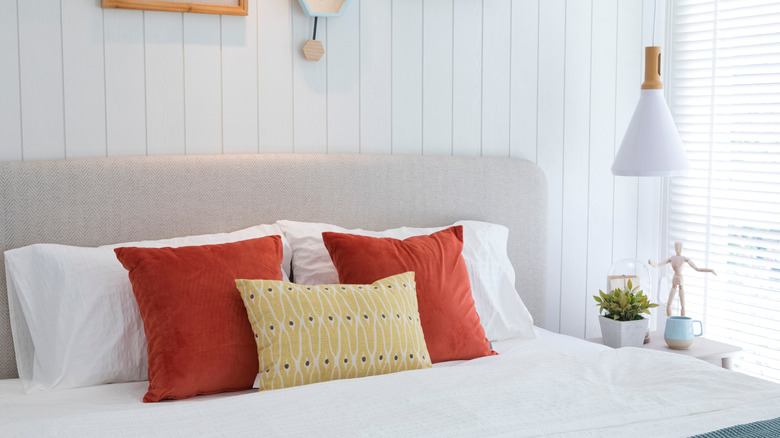 white bedding with orange pillows 