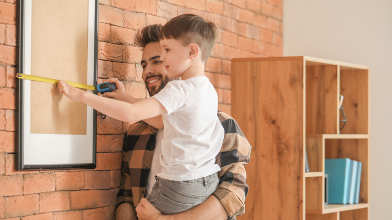 child measuring a wall piece