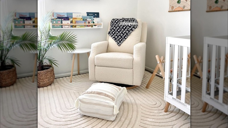 A decorative ottoman is on the floor of a neutral baby nursery