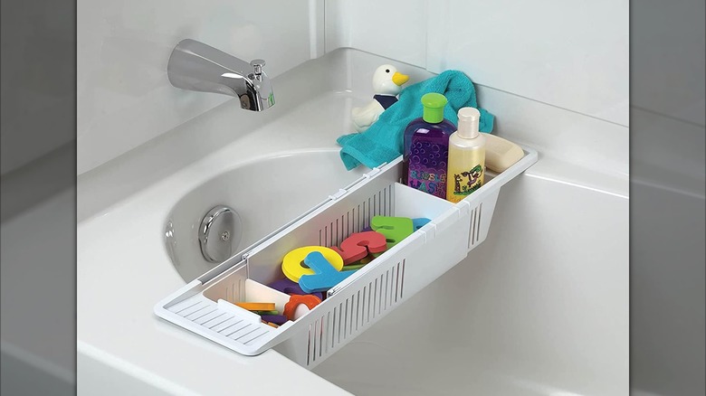 A plastic bath caddy holds kids toys and shampoo