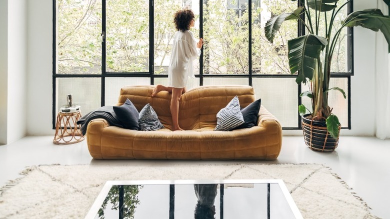 Woman standing on modern sofa