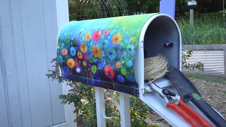 Garden tools stored inside an old decorated mailbox.