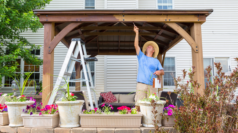 man painting wooden gazebo