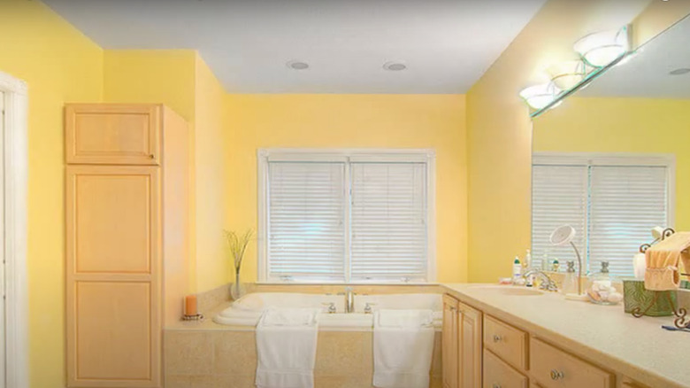 Yellow bathroom with wood cabinetry 