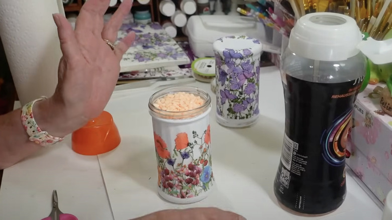 A person fills a decorated parmesan cheese shaker with orange air freshener pellets.