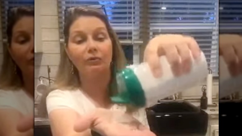 Woman holding up a parmesan cheese container with carpet refresher.