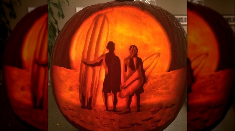 Surfers standing with surfboards pumpkins