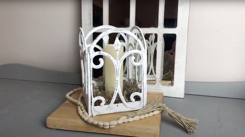 A decorative candle lantern made from Dollar Tree garden fences and a wooden tray