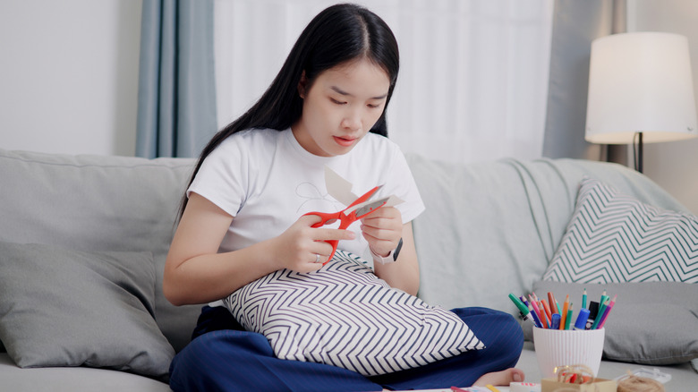 Woman cutting paper while sitting on her couch