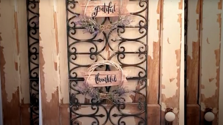 Wreaths with phrases signs affixed to wall decor made from Dollar Tree garden fences