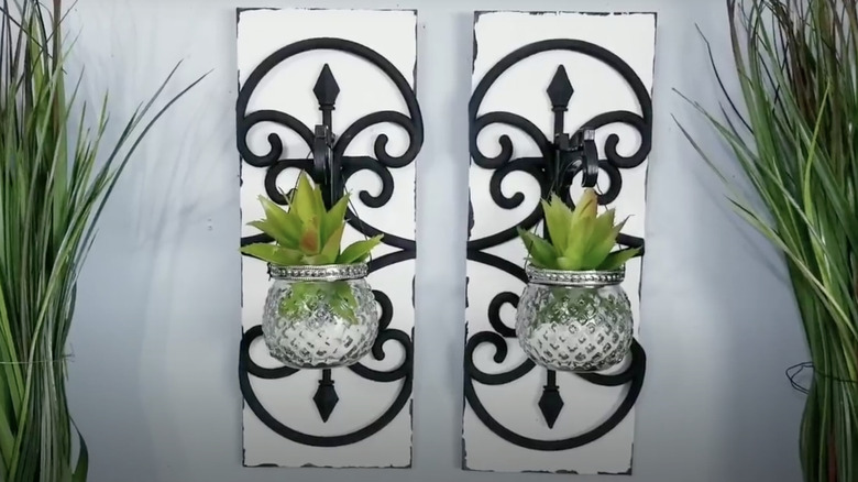 A pair of wall scones with planters for succulents hanging off them