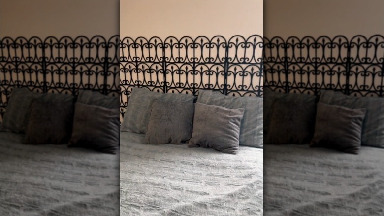 A wrought iron look headboard for a bed made from Dollar Tree garden fences