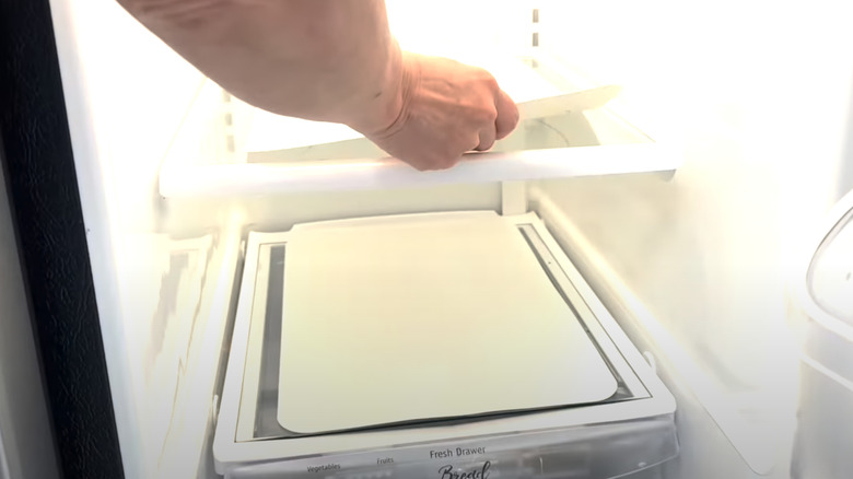 Person putting placemats on fridge shelves to help with cleaning.