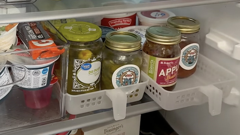 Jars in the fridge in storage baskets with handles.