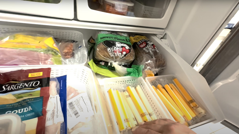 A shelf in the fridge full of food to make sandwiches.