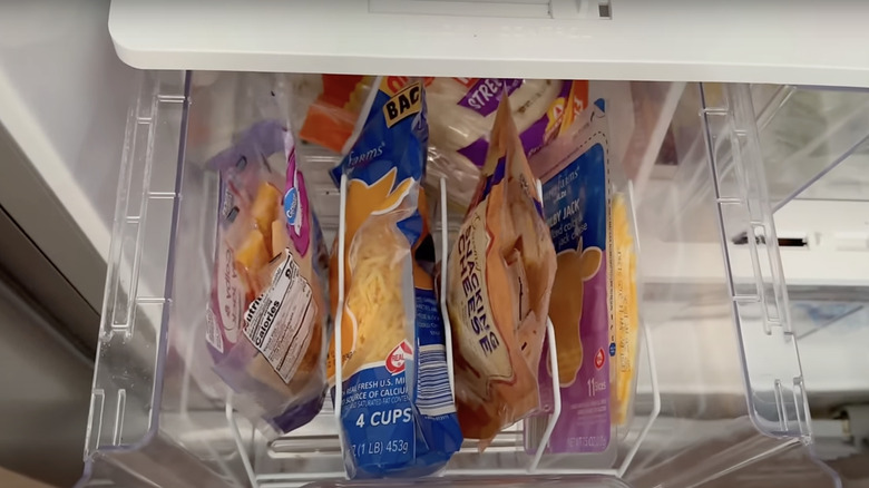 A dryer rack helps you store and sort packets of cheese in the fridge drawer.