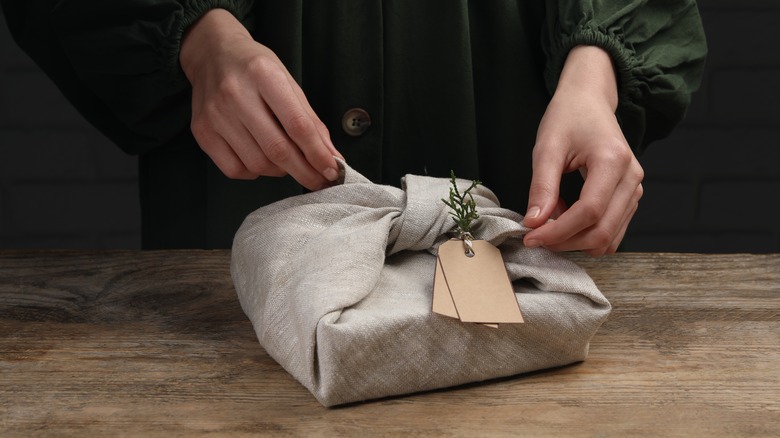 person wrapping gift with fabric