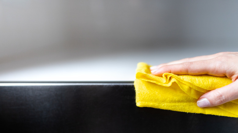 person cleaning with yellow rag