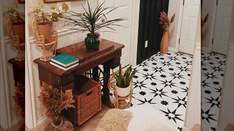 An entryway with black and white tiles, decorated wooden table, and baskets