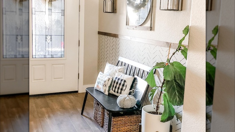 An entryway with a black bench and a lot of cushions