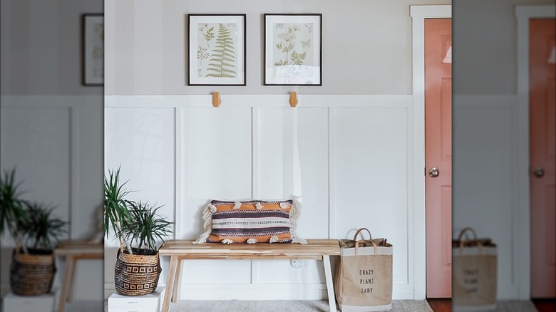 An entryway with art on walls and a bench with a cushion