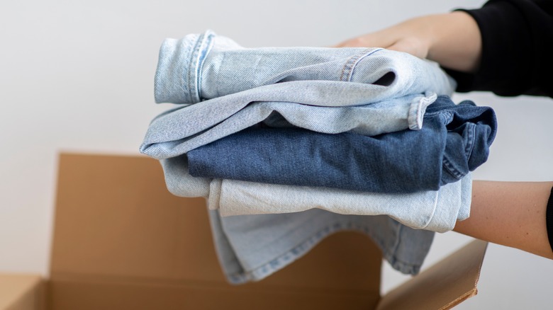 person holding stack of jeans