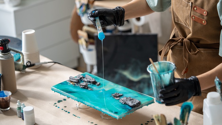 person pouring resin on canvas