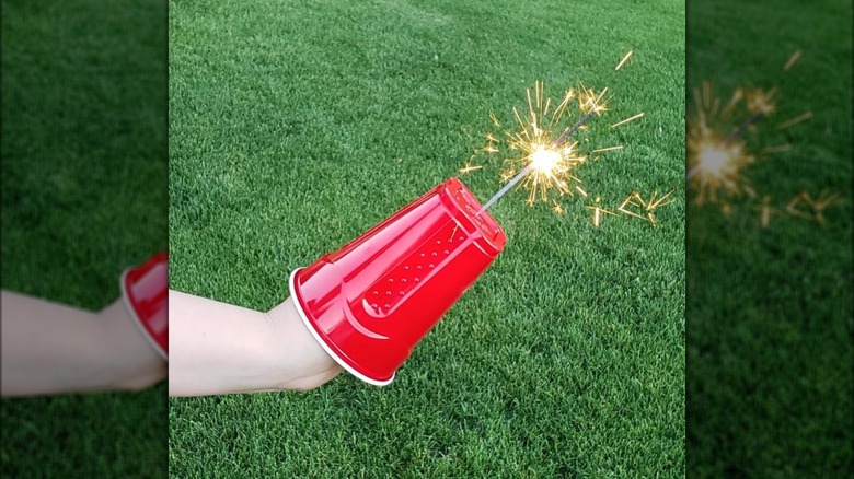 hand in plastic cup holding sparkler