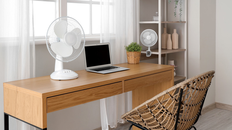 Desk fan on a table beside laptop in a home office