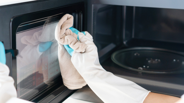 Hand wiping oven door with a microfiber cloth