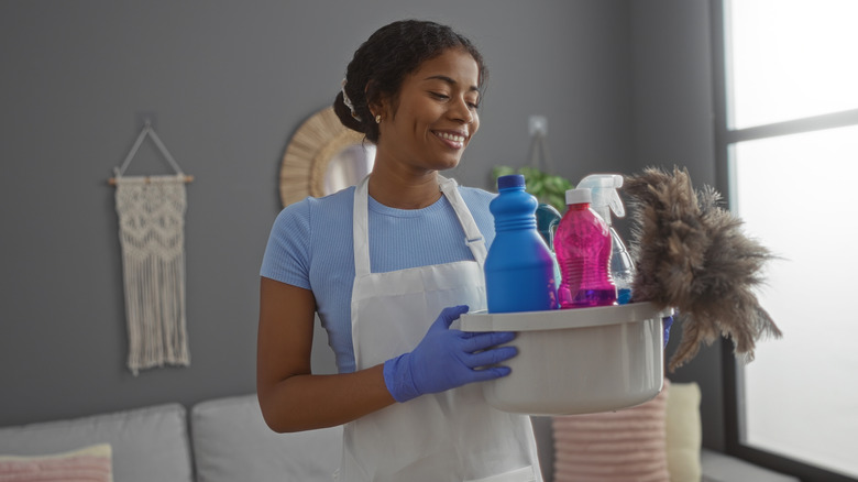 Woman holding basket of cleaning supplies in home