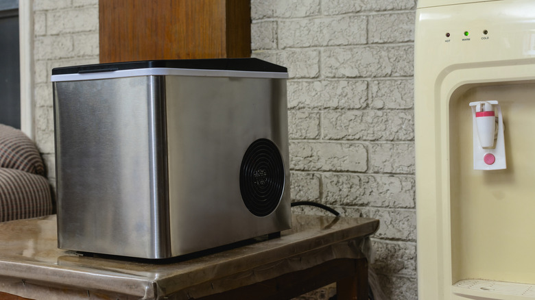 Portable ice maker on a table beside water dispenser