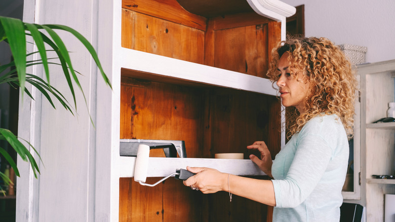 Woman painting an antique cabinet white